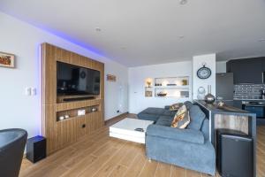 a living room with a blue couch and a tv at Le penthouse des ours in Courseulles-sur-Mer