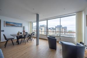 a dining room with a table and chairs and a large window at Le penthouse des ours in Courseulles-sur-Mer