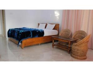 a bedroom with a bed and two chairs and a table at namaste Adoroni Guest House , Manas National Park in Jyoti Gaon +7 photos