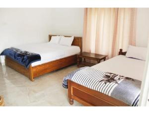 a bedroom with two beds and a night stand at namaste Adoroni Guest House , Manas National Park in Jyoti Gaon