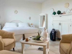a bedroom with a bed and a table and chairs at Borgobianco Resort & Spa Polignano - MGallery Collection in Polignano a Mare