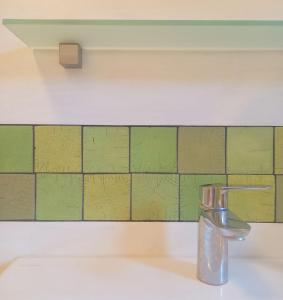 a bathroom sink with a faucet and green tiles at Ferienwohnung Terwey in Geisenhausen