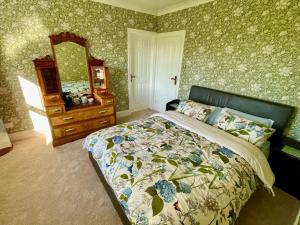 a bedroom with a bed and a dresser and a mirror at Aelybryn in Llangwyryfon +33 photos