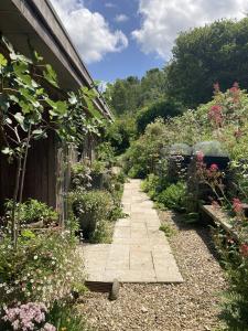 un sentiero nel giardino accanto a una casa con fiori di The Sanctuary Cornwall a Golant