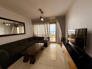 a living room with a couch and a flat screen tv at Royal King David Apartment in Netanya