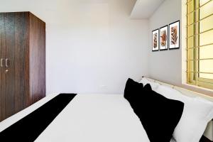 Un dormitorio con una cama con almohadas blancas y negras. en Hotel O AAFA SUITES Sri Venkateshwara Theatre, en Bangalore