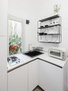 a white kitchen with a sink and a microwave at Casa Dona - Essenza in Catania