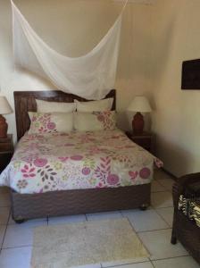 Un dormitorio con una cama con sábanas y almohadas rosas y blancas. en Tabonina Guesthouse, en Livingstone