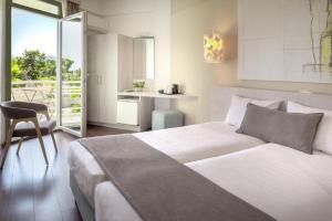 a bedroom with a large white bed and a chair at The Grove Seaside Hotel in Drepana