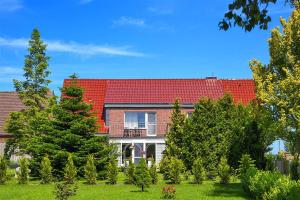 a brick house with a red roof and trees at Hof Lueck in Esens