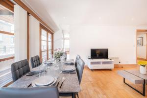 Un comedor con mesa y sillas y un televisor. en BnBNova - 2BR Penthouse with Terrace - Heart of Holborn, en Londres