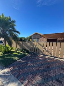 a fence in front of a house with a brick driveway at Magic Shot Jeffreys Bay in Jeffreys Bay