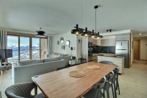 eine Küche und ein Wohnzimmer mit einem Holztisch und Stühlen in der Unterkunft ARC 1600, LE RIDGE, Appartement 10 personnes Vue Montagne - ski aux pieds - Sauna, Hammam, Piscine in Arc 1600