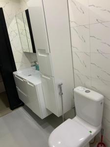 Un baño blanco con inodoro y espejo. en Appartement meublé de rêve, en Dakar