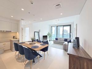 a kitchen and living room with a table and chairs at Deluxe 1-Bedroom in The Grand - Waterfront and Skyline Views in Dubai