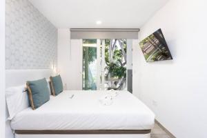 a bedroom with a white bed with a window at Sunnyland Teresitas beach house in San Andrés