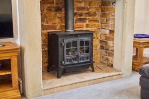 a stove in a living room with a brick wall at Host & Stay - Pier View in Amble