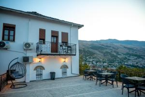 a white building with tables and chairs on a balcony at Traditional House & Rooms Shapllo in Gjirokastër