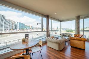 a living room with a large window and a table and chairs at Abba Playa Gijón in Gijón