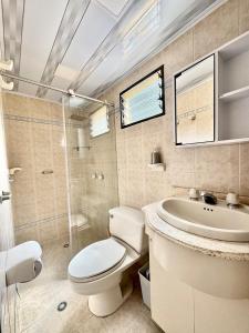 a white bathroom with a toilet and a sink at Casa hotel la 33 in Medellín