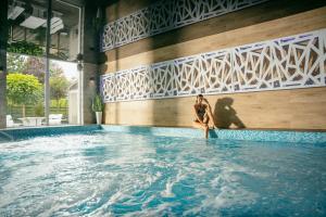 a woman sitting in the water in a swimming pool at Tramontana Family & Wellness in Darlowko