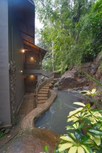 a house with a staircase leading to a river at Alaya Stays Panchavadi Farm Stay in Thekkady