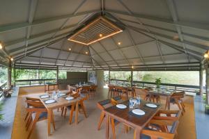 a restaurant with wooden tables and wooden chairs at Alaya Stays Panchavadi Farm Stay in Thekkady +79 photos