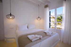 普拉迪斯亚罗斯Seethrough Mykonos Suites的一间白色的卧室，有一张大床，上面放着毛巾 更多37张照片