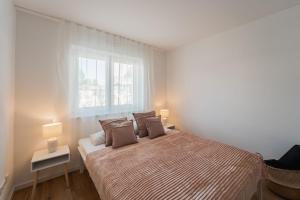 ein Schlafzimmer mit einem Bett mit zwei Lampen und einem Fenster in der Unterkunft Bay 47° Boutique Apartments am Chiemsee in Übersee