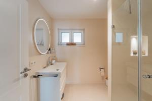 ein weißes Badezimmer mit Waschbecken und Spiegel in der Unterkunft Bay 47° Boutique Apartments am Chiemsee in Übersee + 25 Fotos