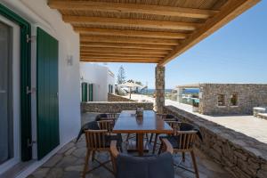 普拉迪斯亚罗斯Seethrough Mykonos Suites的户外庭院配有木桌和椅子