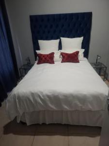 a large white bed with two red pillows on it at 77 Pendleberry Grove in Warmbaths