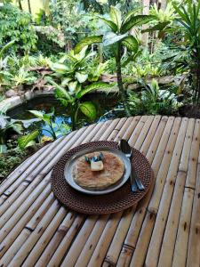 a plate of food sitting on a wooden table at Tree bamboo house in Tampaksiring