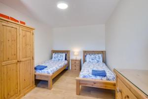 two twin beds in a room with a cabinet at Bluebell Cottage in Penclawdd