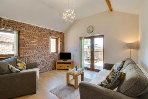 a living room with two couches and a brick wall at Bluebell Cottage in Penclawdd
