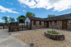 a stone house with a fence and a yard at Bluebell Cottage in Penclawdd