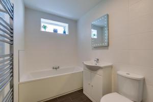 a bathroom with a toilet and a sink and a bath tub at Bluebell Cottage in Penclawdd +2 photos