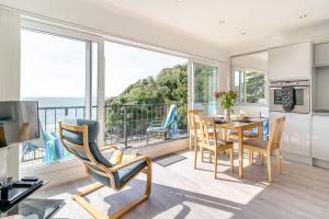 a living room with a table and chairs and a balcony at 9_306B Redcliffe Apartments, Caswell Bay in Bishopston