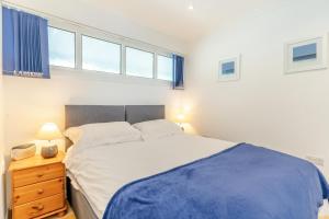 a bedroom with a bed and a nightstand and windows at 9_306B Redcliffe Apartments, Caswell Bay in Bishopston