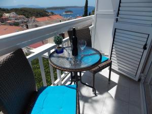 a glass table on a balcony with two chairs at Apartments and Rooms Jasna in Hvar