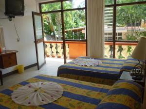 波多埃斯康迪的住宿－Rincon del Pacifico，两张带遮阳伞的床(位于客房内)