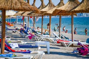 a group of chairs and umbrellas on a beach at Complex Modern All Inclusive Mamaia in Mamaia
