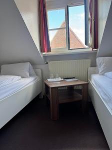 a room with two beds and a table with a window at Greetsieler Börse in Greetsiel