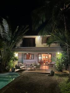 a house with a swimming pool at night at Jeevan Palm House in Petite Case Noyale