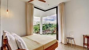 サン・ドニにあるVilla Cacao - avec piscine et vue mer - Nosy Beのベッドと大きな窓のある寝室 +17枚の写真