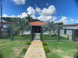 a house with palm trees and a brick walkway at Casa de 3 quartos com piscina in Laranjeiras do Sul