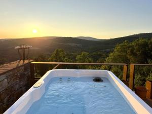 a hot tub on a balcony with the sunset at Barrieiro - Art & Nature in Marvão
