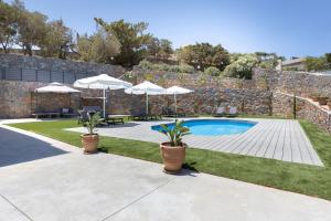 Una piscina con sombrillas y plantas en un patio. en Villa Calissea, en Agia Pelagia