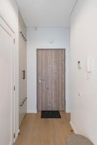 a hallway with a wooden door in a white room at Saulės Sonata apartamentai 5 in Druskininkai