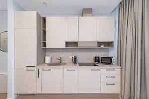 a kitchen with white cabinets and a sink at Saulės Sonata apartamentai 5 in Druskininkai